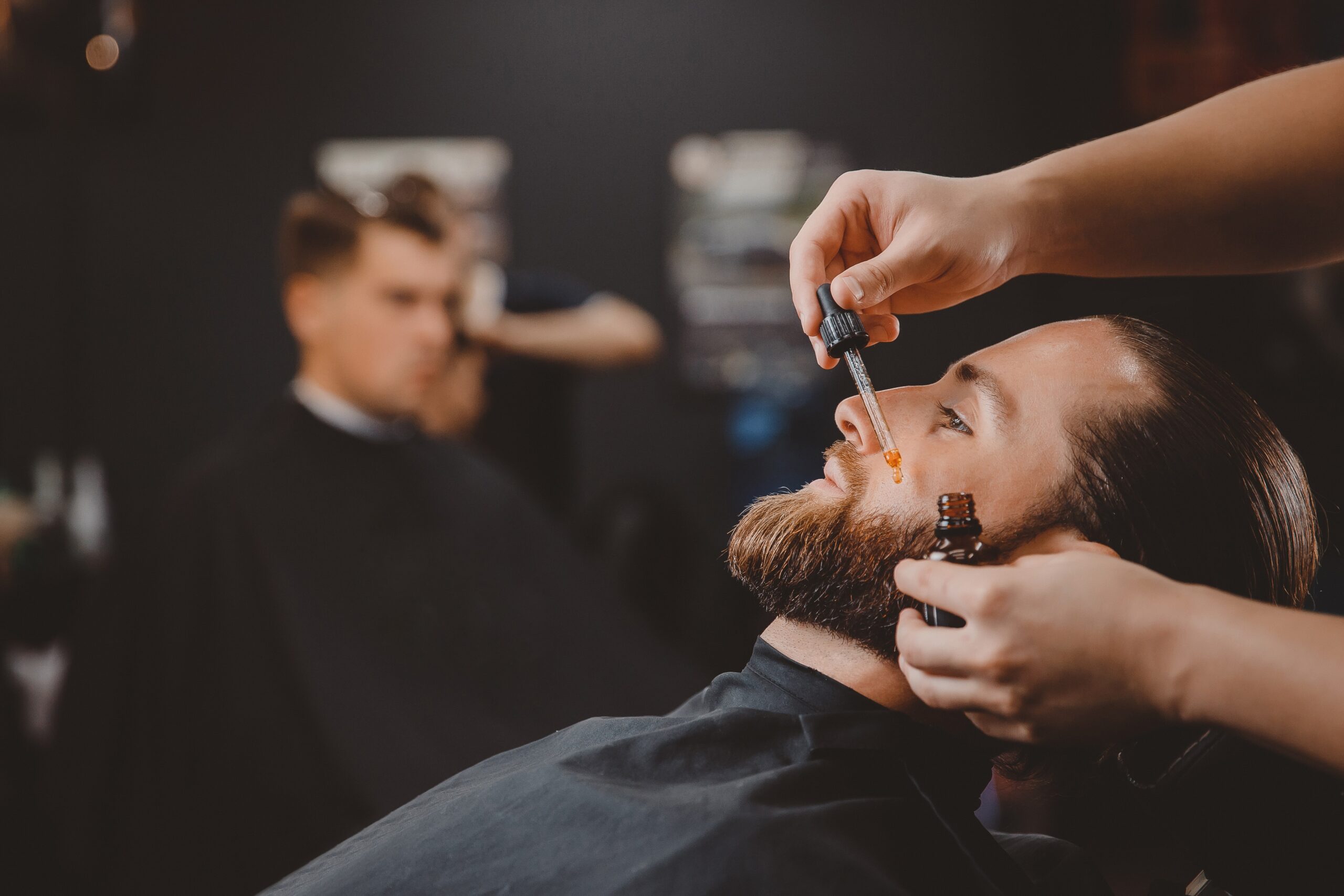 Barber applying beard oil to customer