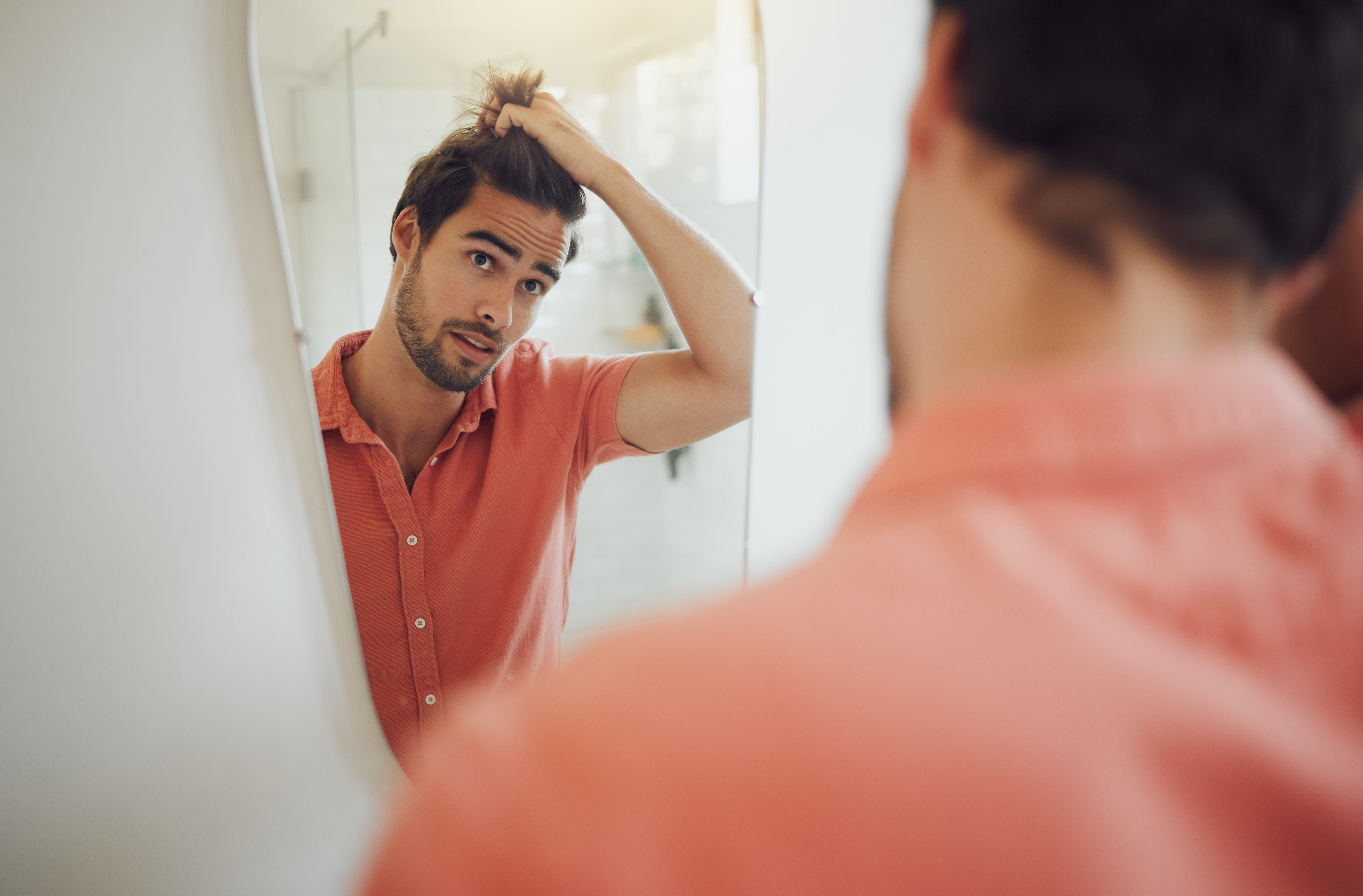 Man looking at hair in the mirror