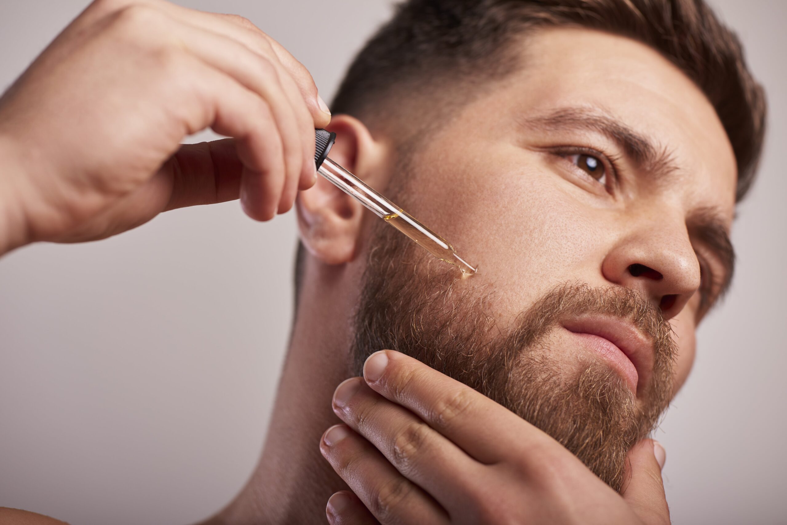 Man applying oil to his beard with dropper