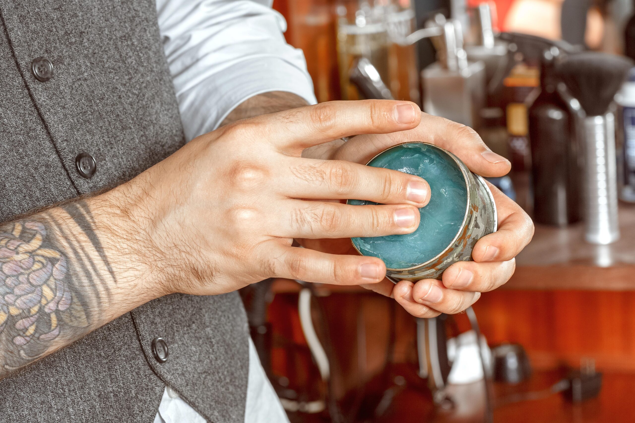 Close-up of barber dipping fingers into jar of hair product