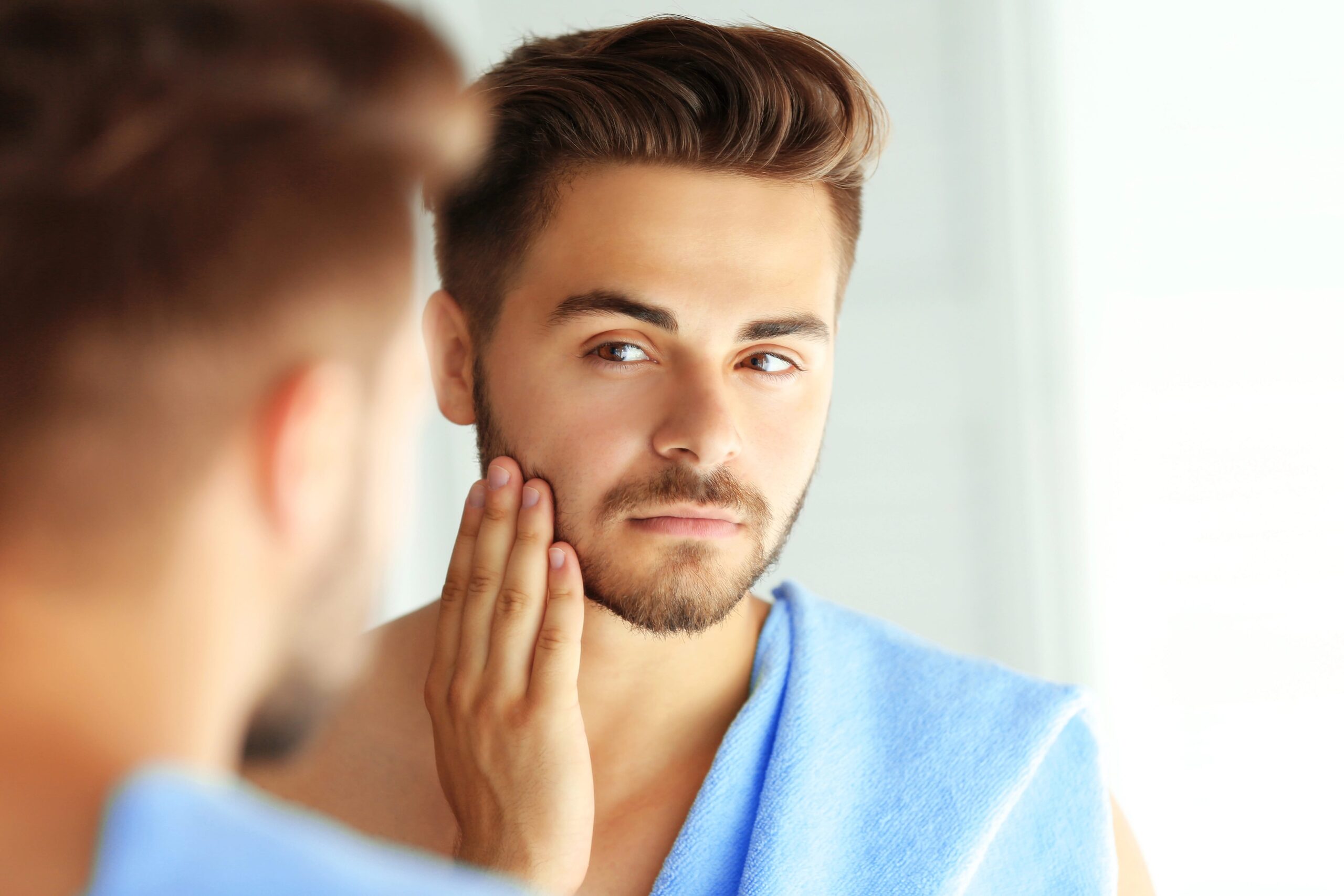 Young man looking at beard in mirror