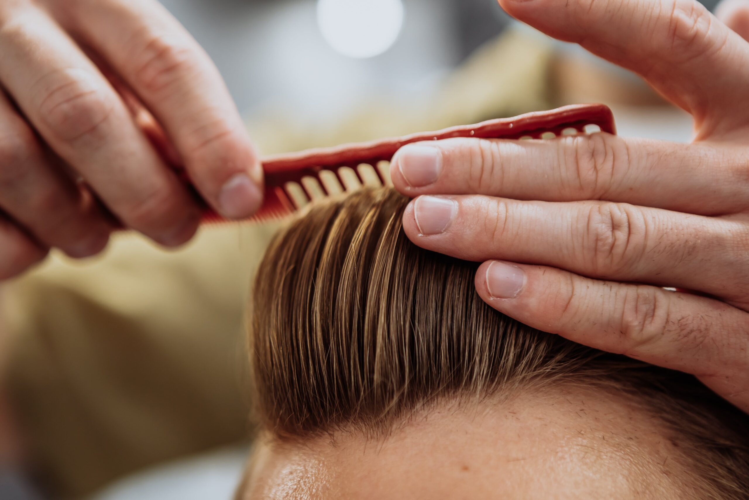 Close-up of barber combing top of hair