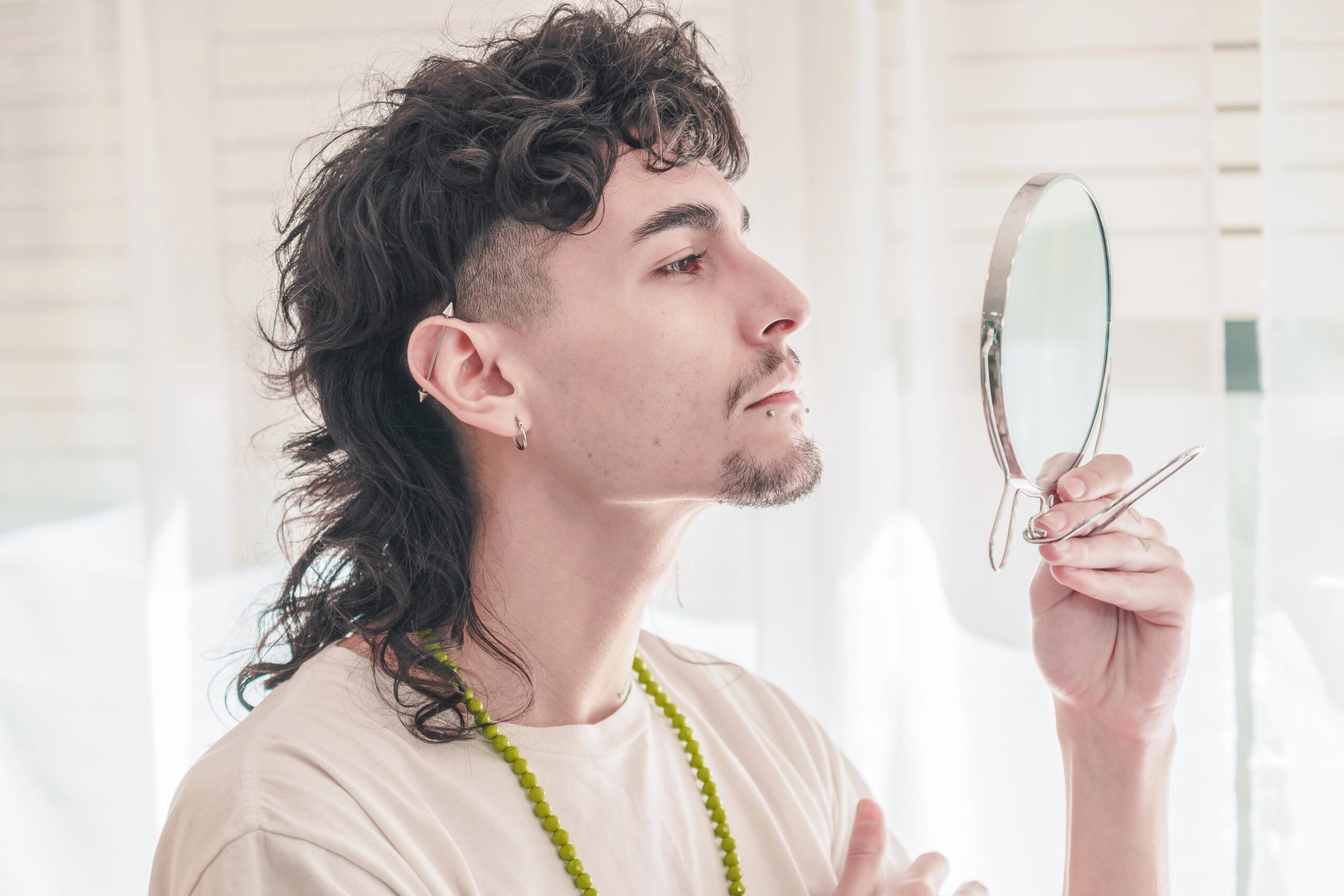 Hip man with modern mullet looking at himself in mirror